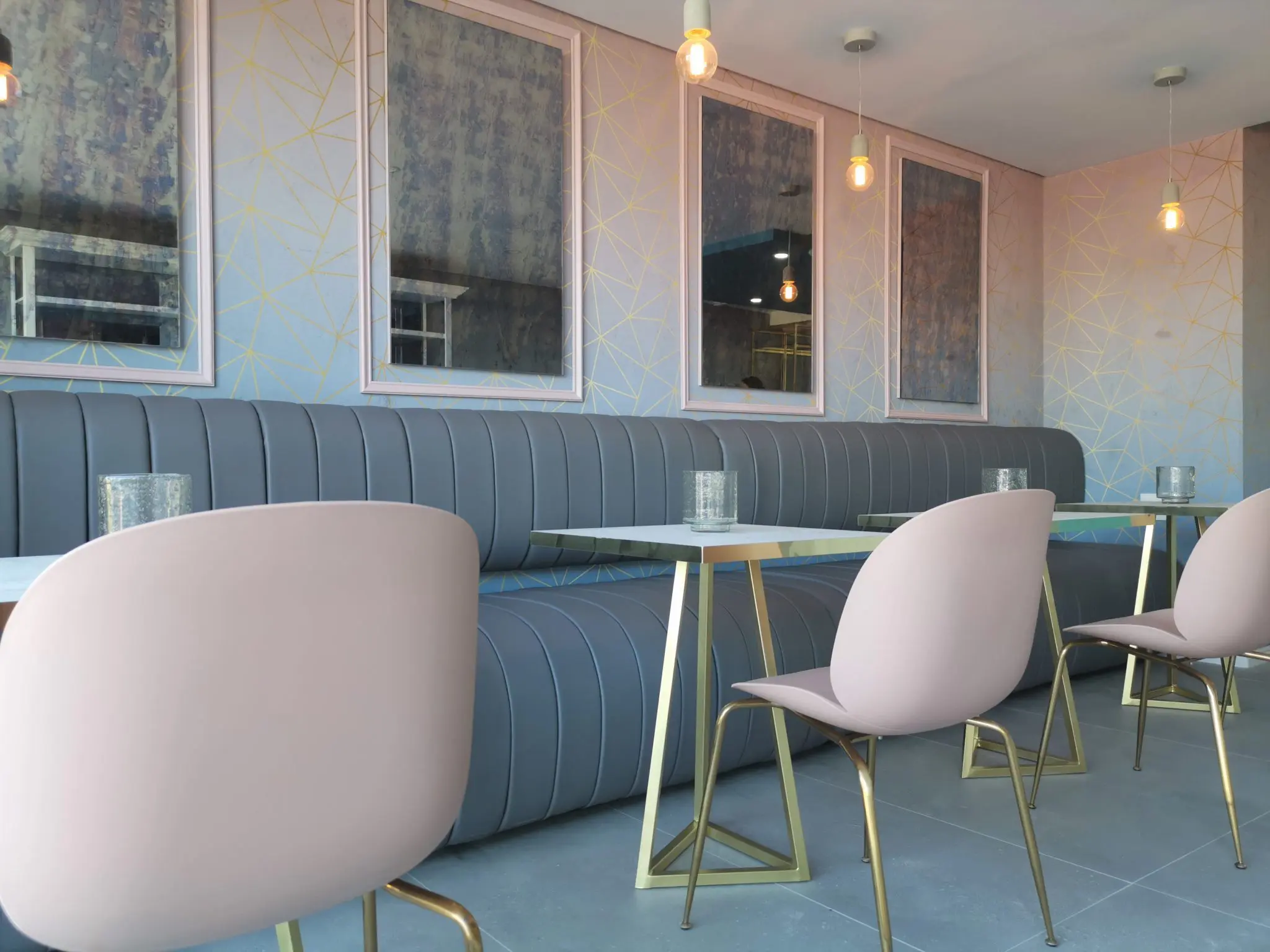retail design built in booth seat with pleated vinyl fabric, smoked glass mirrors with pink frames, geometric wallpaper design, gold details