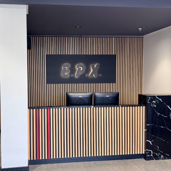 reception desk with finishes of natural oak slats black onyx stone and EPX backlit logo
