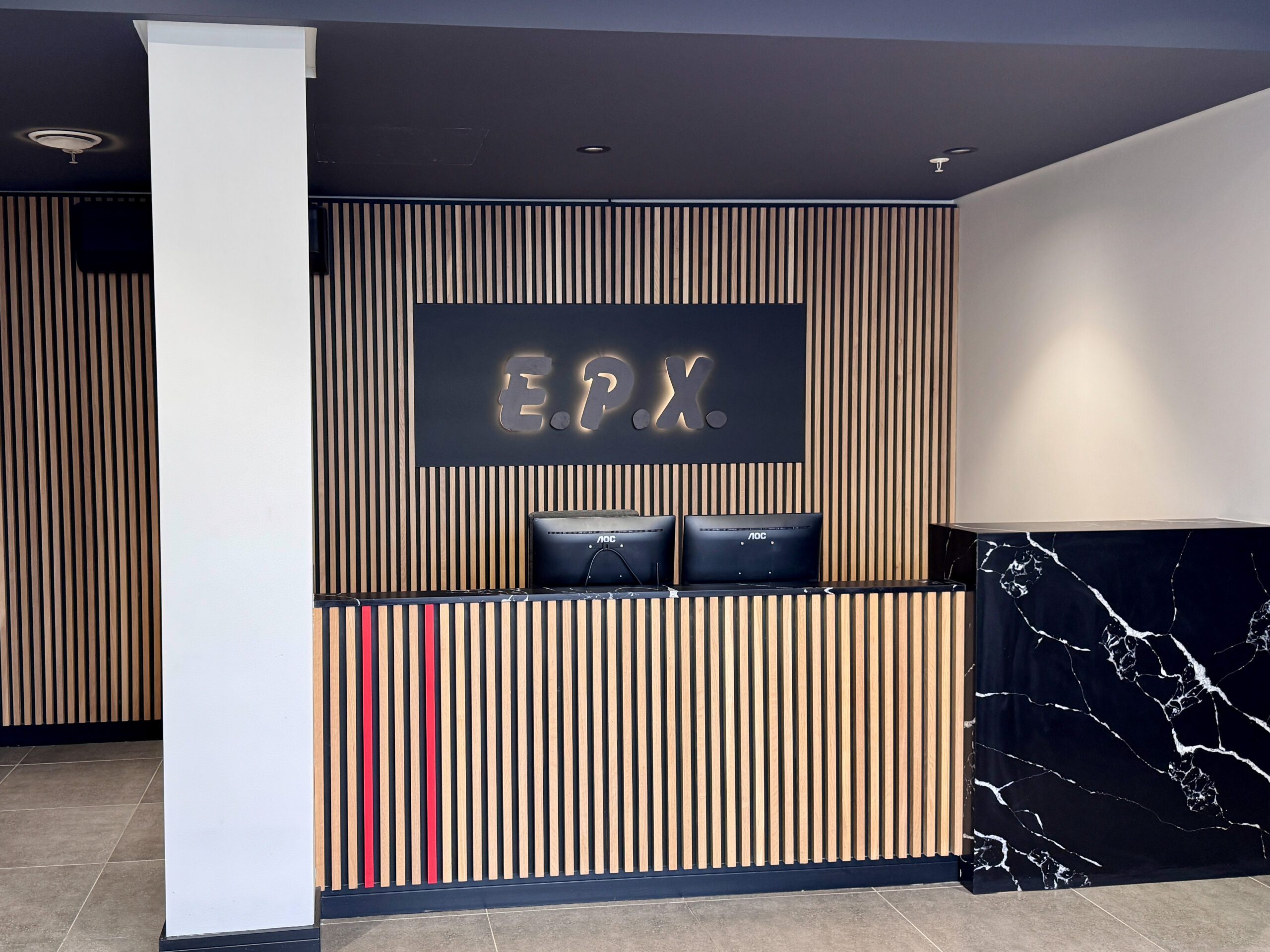 reception desk with finishes of natural oak slats black onyx stone and EPX backlit logo